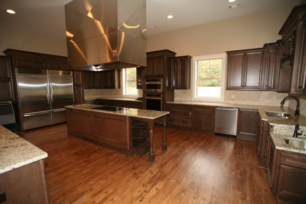 A modern kitchen with wood flooring and stainless steel appliances.
