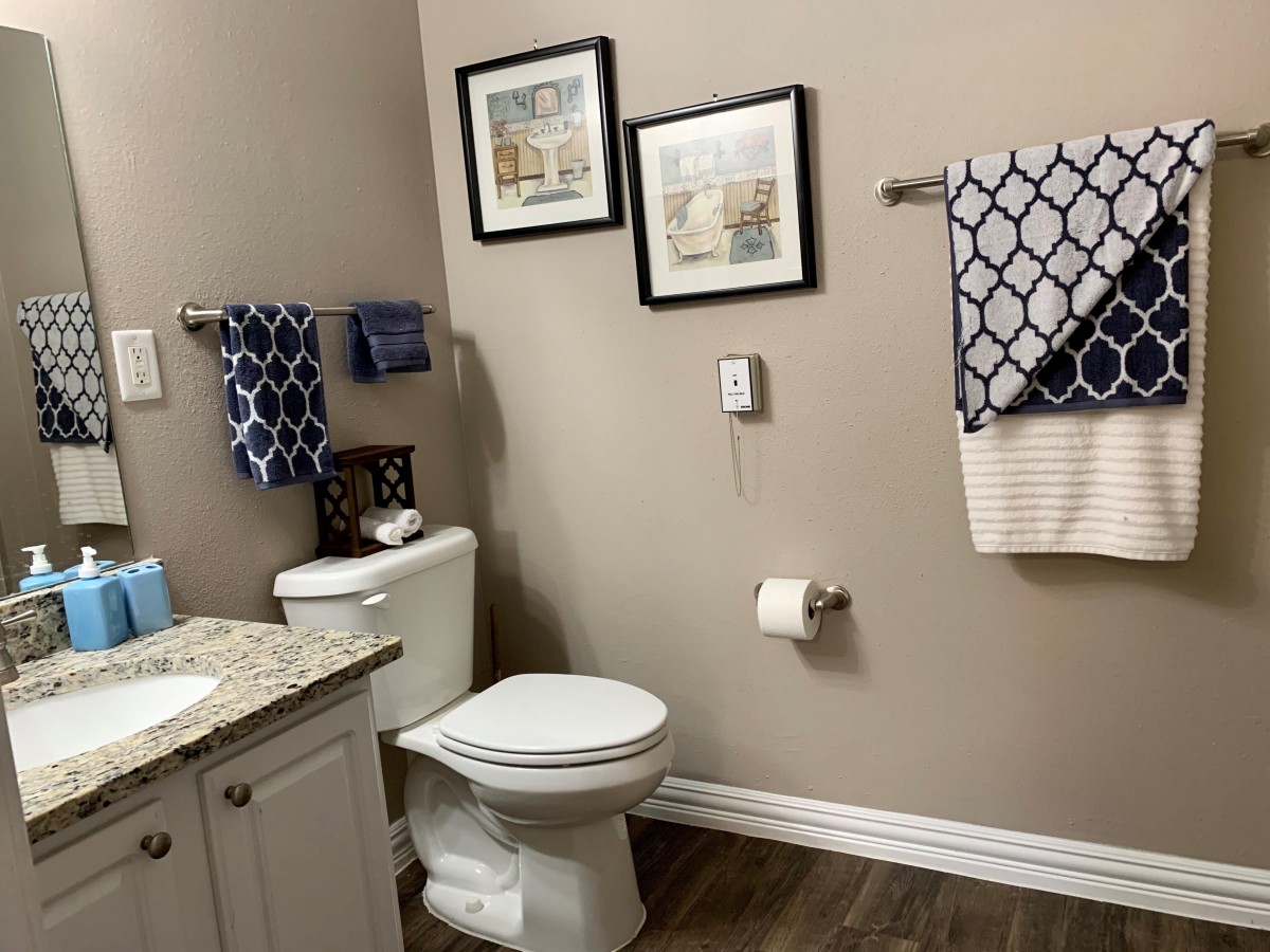 A neatly decorated bathroom with framed wall art, patterned towels, and a clean countertop.