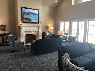 A cozy living room with sofas, a fireplace, and large windows letting in natural light.