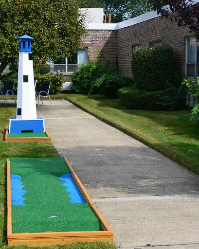 A brightly colored lighthouse marks a hole on a miniature golf course, surrounded by well-maintained grass and pathways.