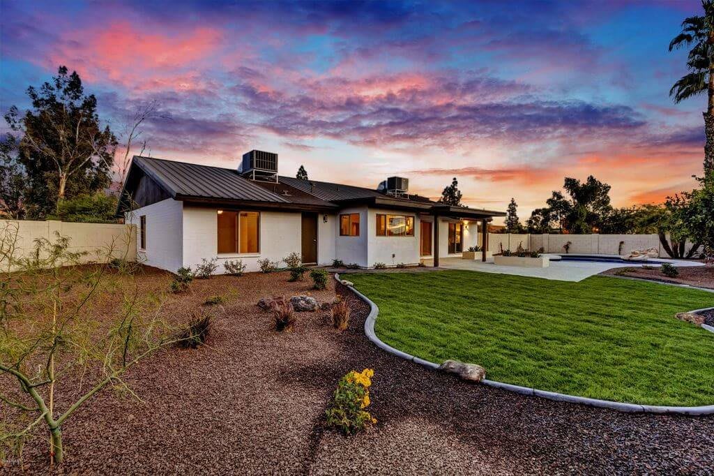 A modern house with a well-maintained yard and garden at sunset.