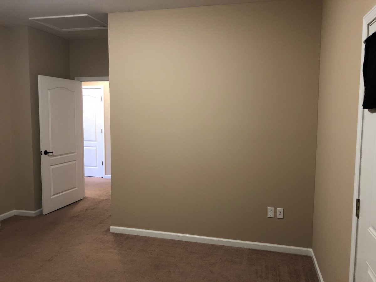 An empty room with beige walls and a carpeted floor.