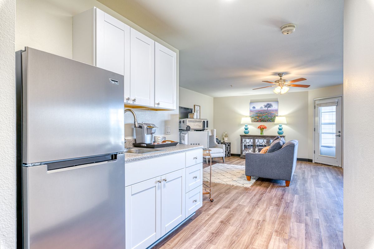 A modern open-concept kitchen and living room with hardwood floors and stainless steel appliances.