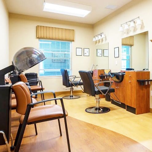 An empty hair salon with chairs, mirrors, and a dryer.