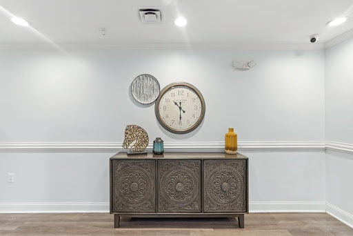 A stylish interior setup featuring a decorative cabinet, wall clock, and artistic elements.