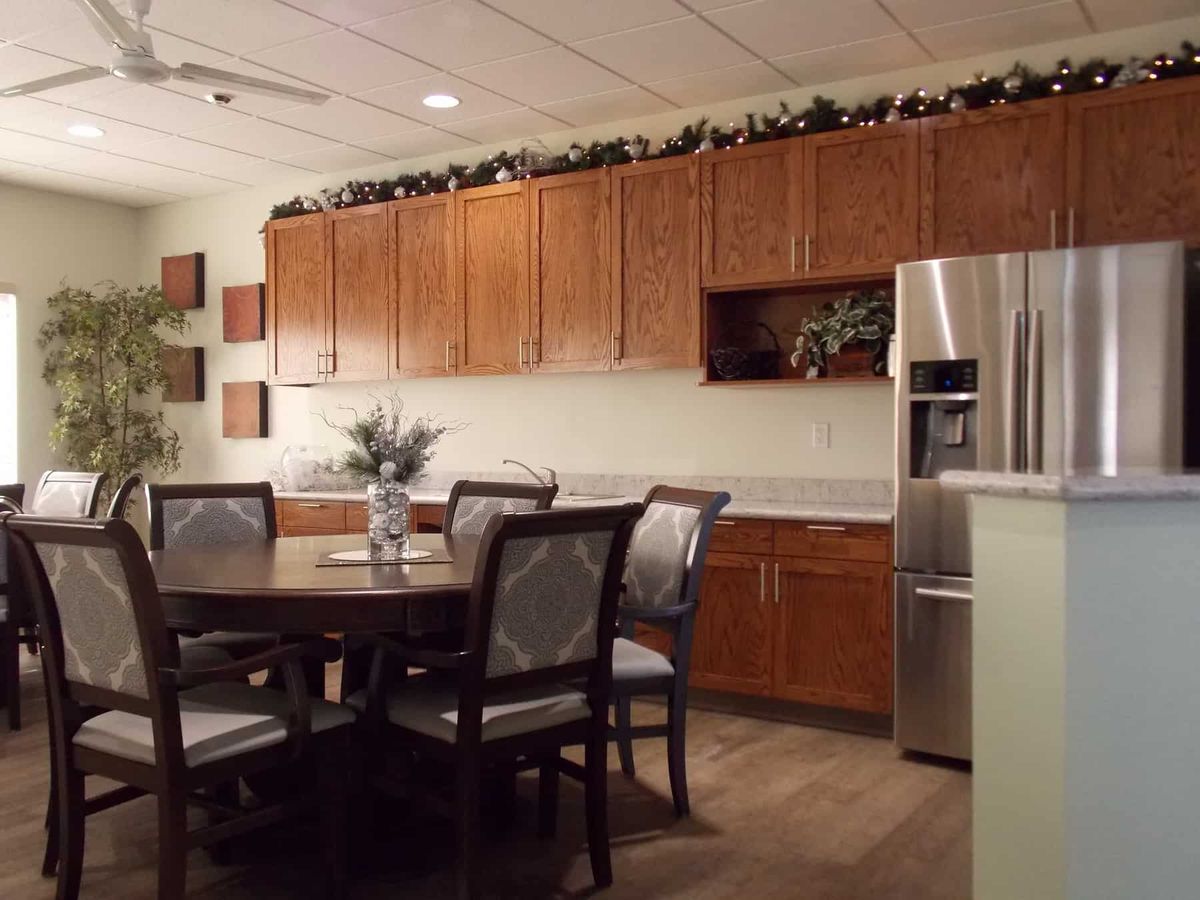 A cozy kitchen and dining area featuring wooden cabinets, a round dining table with chairs, and a stainless steel refrigerator.