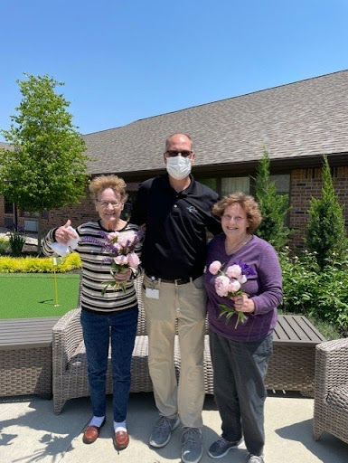 A joyful moment shared among friends in the garden, celebrating with flowers.