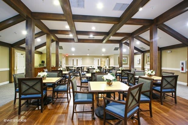 Spacious dining area with wooden beams and neatly arranged tables and chairs.