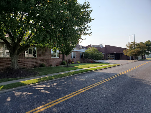 A quiet residential street with trees lining the sidewalk and buildings in view.