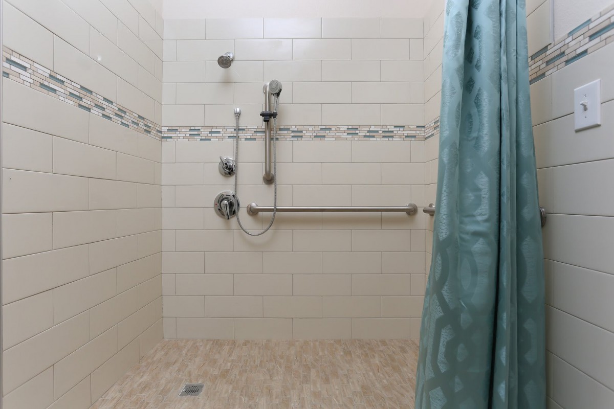 A tiled shower area with a grab bar and curtain.