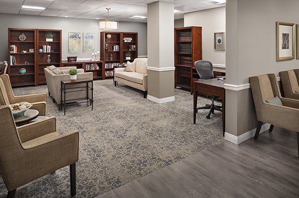 A spacious and well-furnished office lobby with comfortable seating and bookshelves.