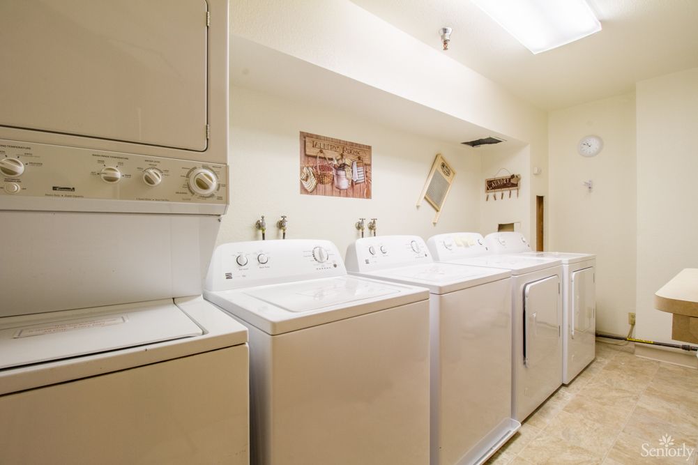 A spacious laundry room featuring multiple washing machines and dryers.