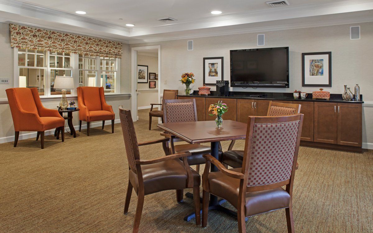A cozy living room with a dining table and chairs, a large television on the wall, and comfortable seating.