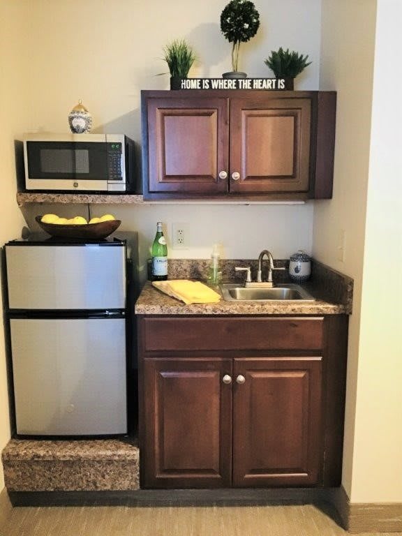 A compact kitchenette with a microwave, refrigerator, and cabinetry.