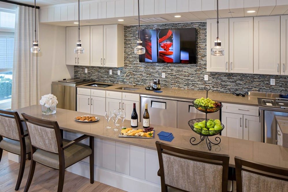 Modern kitchen with a stylish backsplash, featuring a countertop bar with wine and fruit.