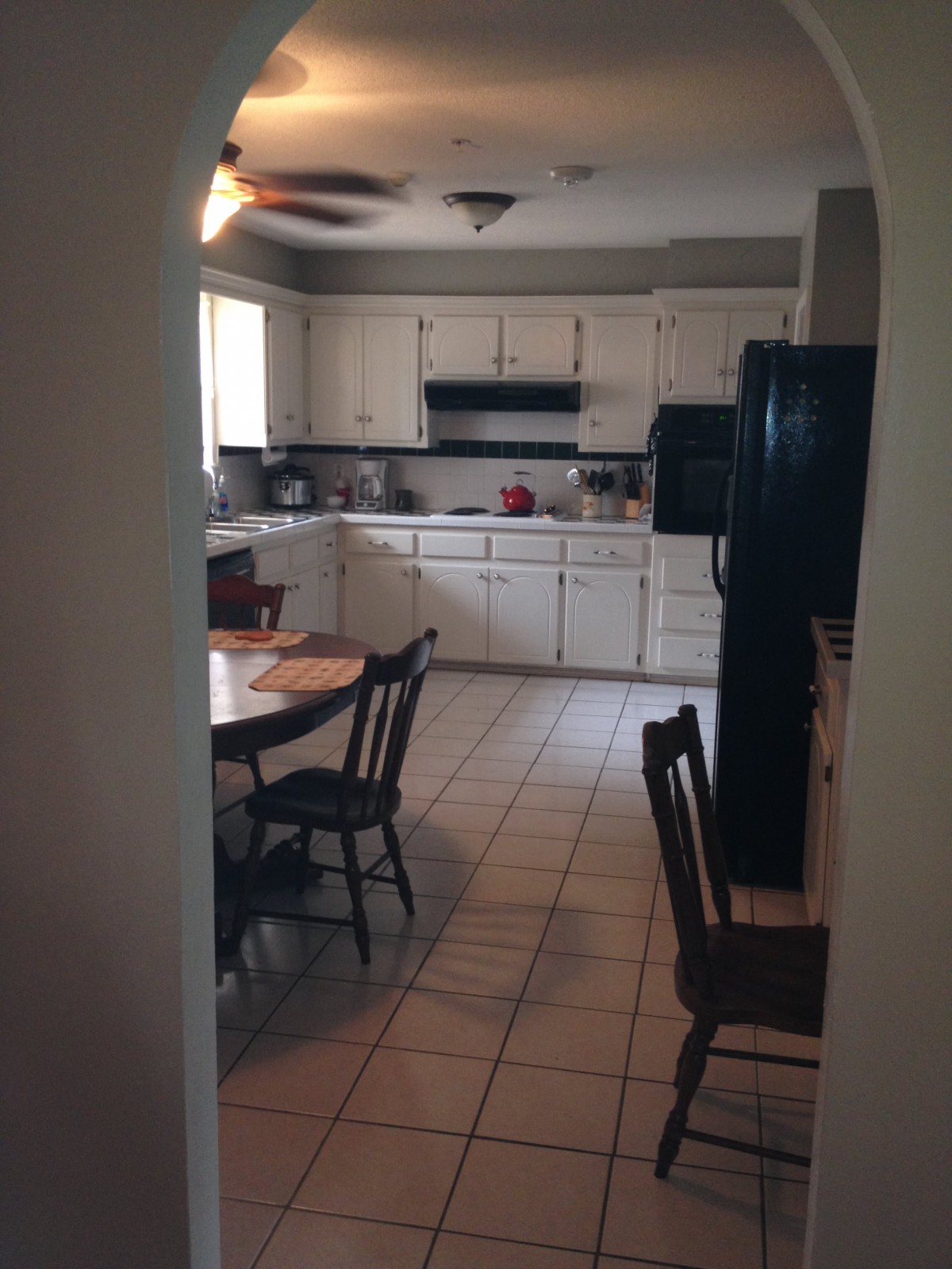 A view of a kitchen and dining area with white cabinets, a table, and chairs.
