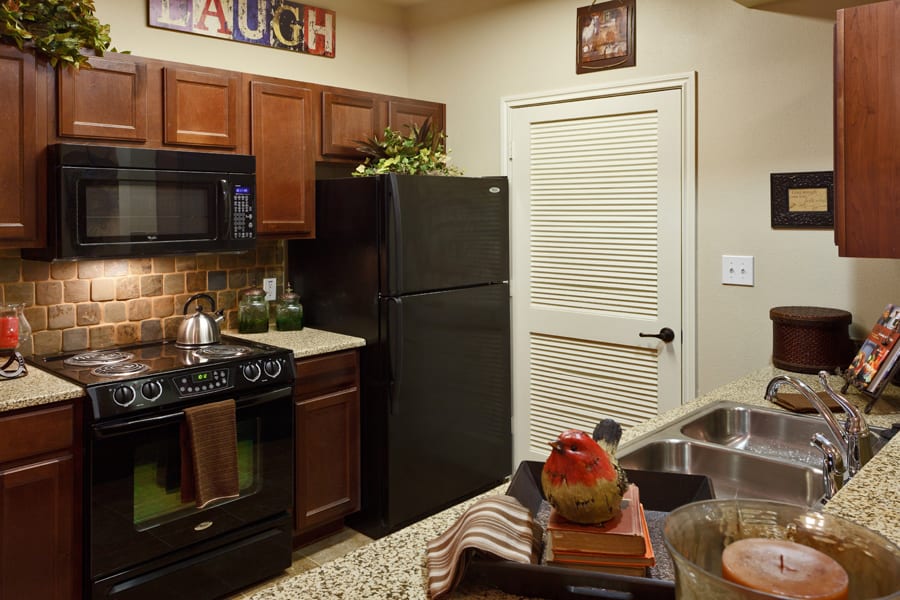 A cozy kitchen with wooden cabinets, black appliances, and decorative elements.