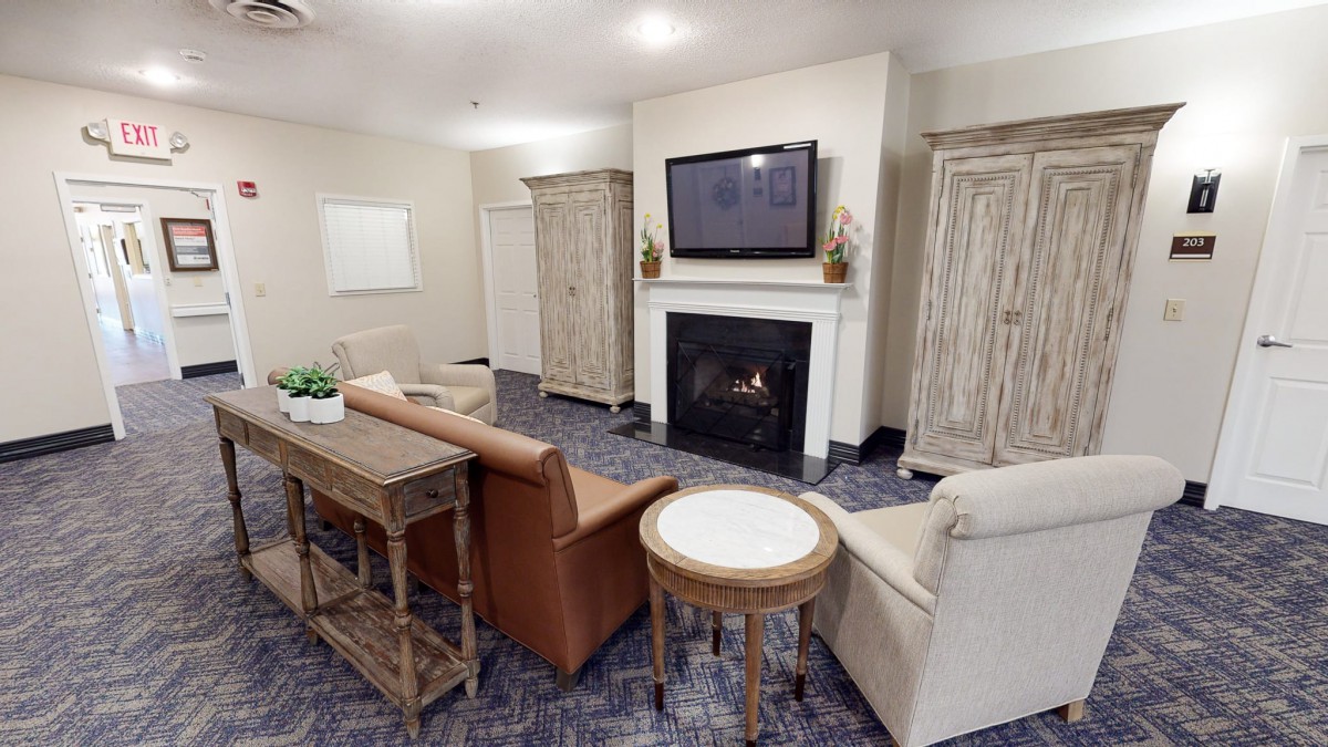 A cozy living room with a fireplace and TV, featuring comfortable seating and wooden furniture.
