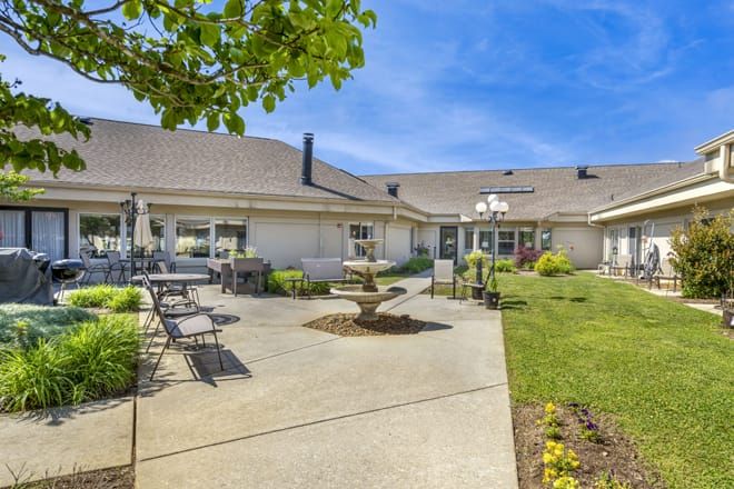 Spacious backyard with patio furniture and a well-maintained garden on a sunny day.