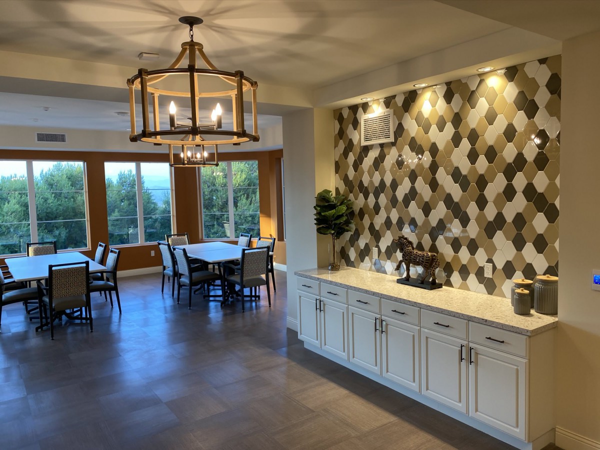 A modern dining room with a stylish chandelier and large windows offering a view.