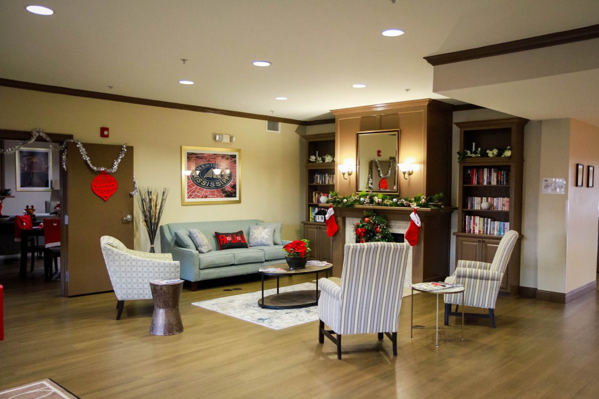 A cozy living room with holiday decorations, featuring comfortable seating and a fireplace.