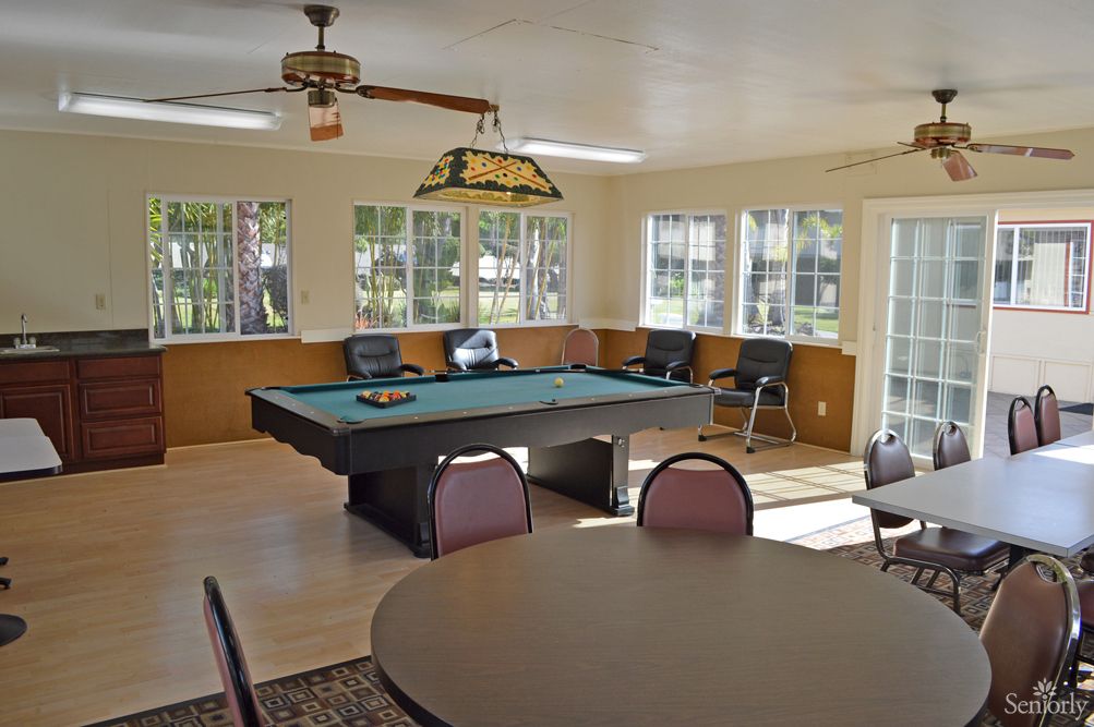 A well-lit game room featuring a billiards table and seating area.