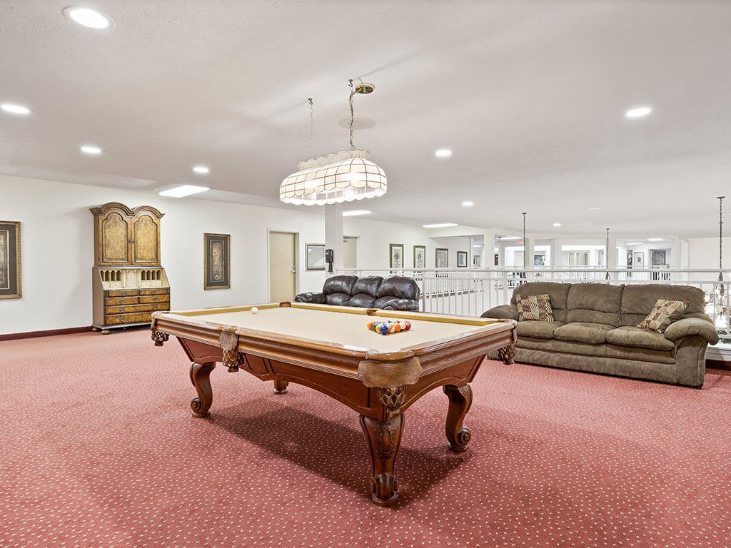 A spacious recreational room featuring a pool table, sofas, and elegant lighting.