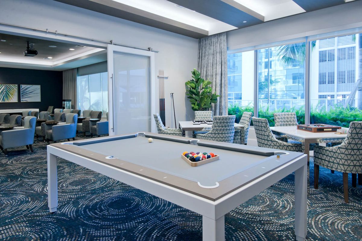A modern game room featuring a pool table and stylish decor with ample natural light.