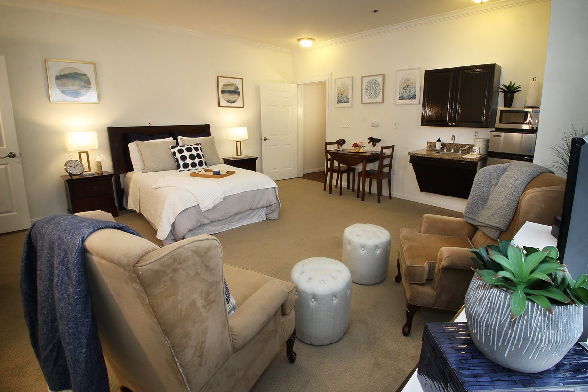 A cozy studio apartment featuring a comfortable bed, seating area, and dining table.