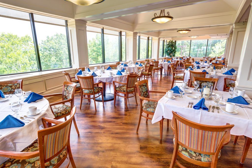 An elegant restaurant dining room with neatly arranged tables and large windows.