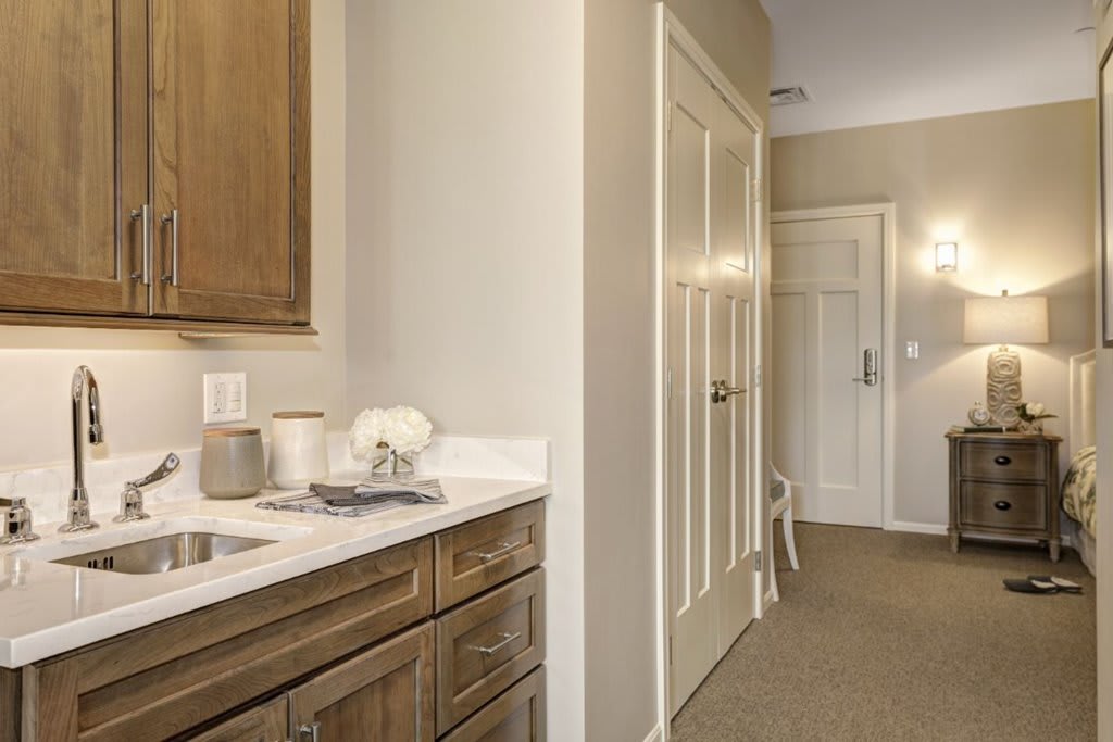A hallway with wooden cabinets, neutral color tones, and a carpeted floor.