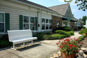 A charming building with a white bench, colorful flowers, and well-maintained landscaping.