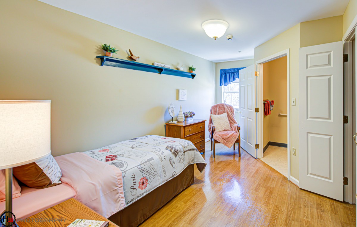 A cozy bedroom with a single bed, wooden floor, and decorative shelf.