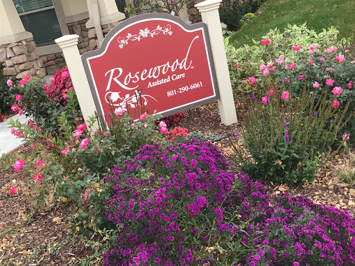 A vibrant garden featuring colorful flowers alongside the Rosewood sign.