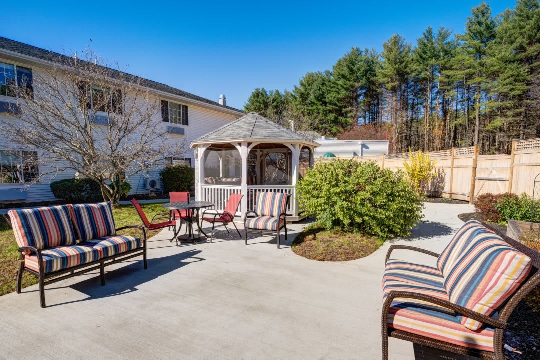 A spacious backyard patio with seating and a gazebo on a sunny day.