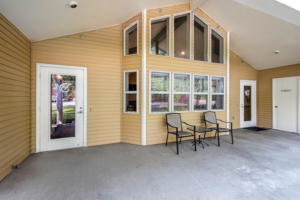A cozy patio with two chairs and large windows.