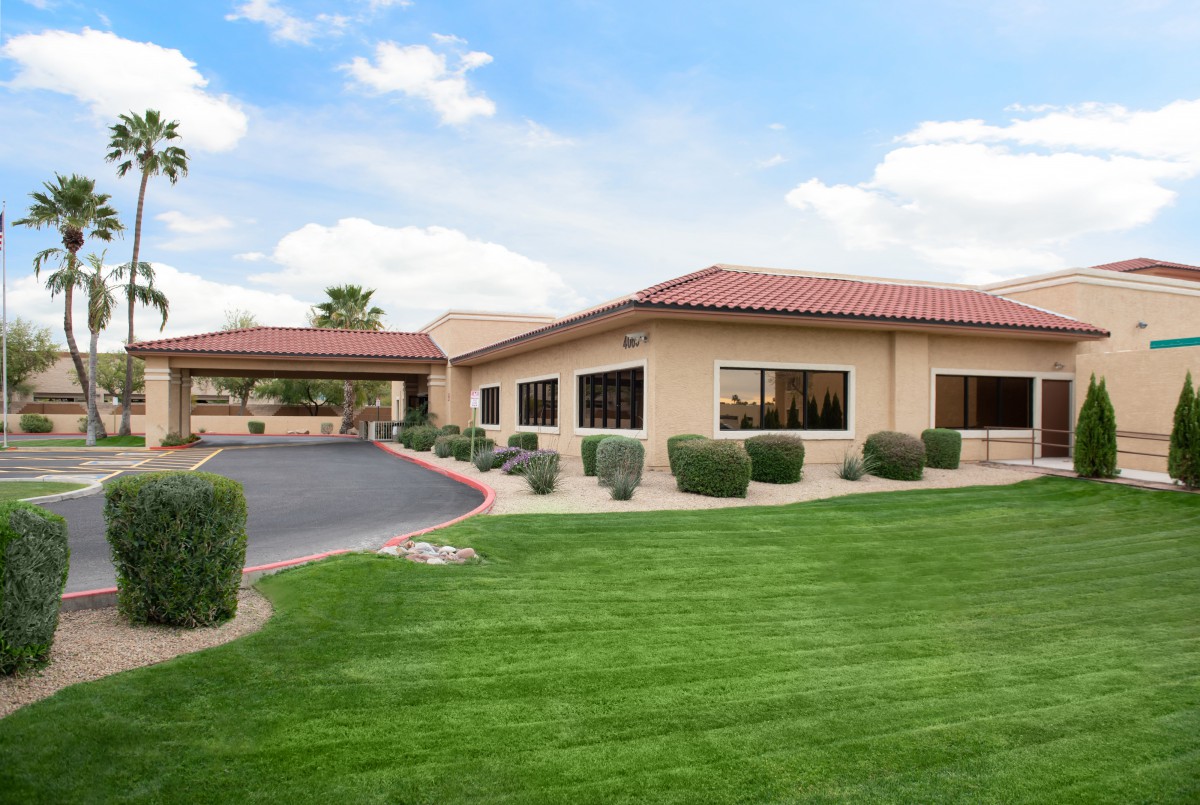 A landscaped building with a red-tiled roof under a partly cloudy sky.
