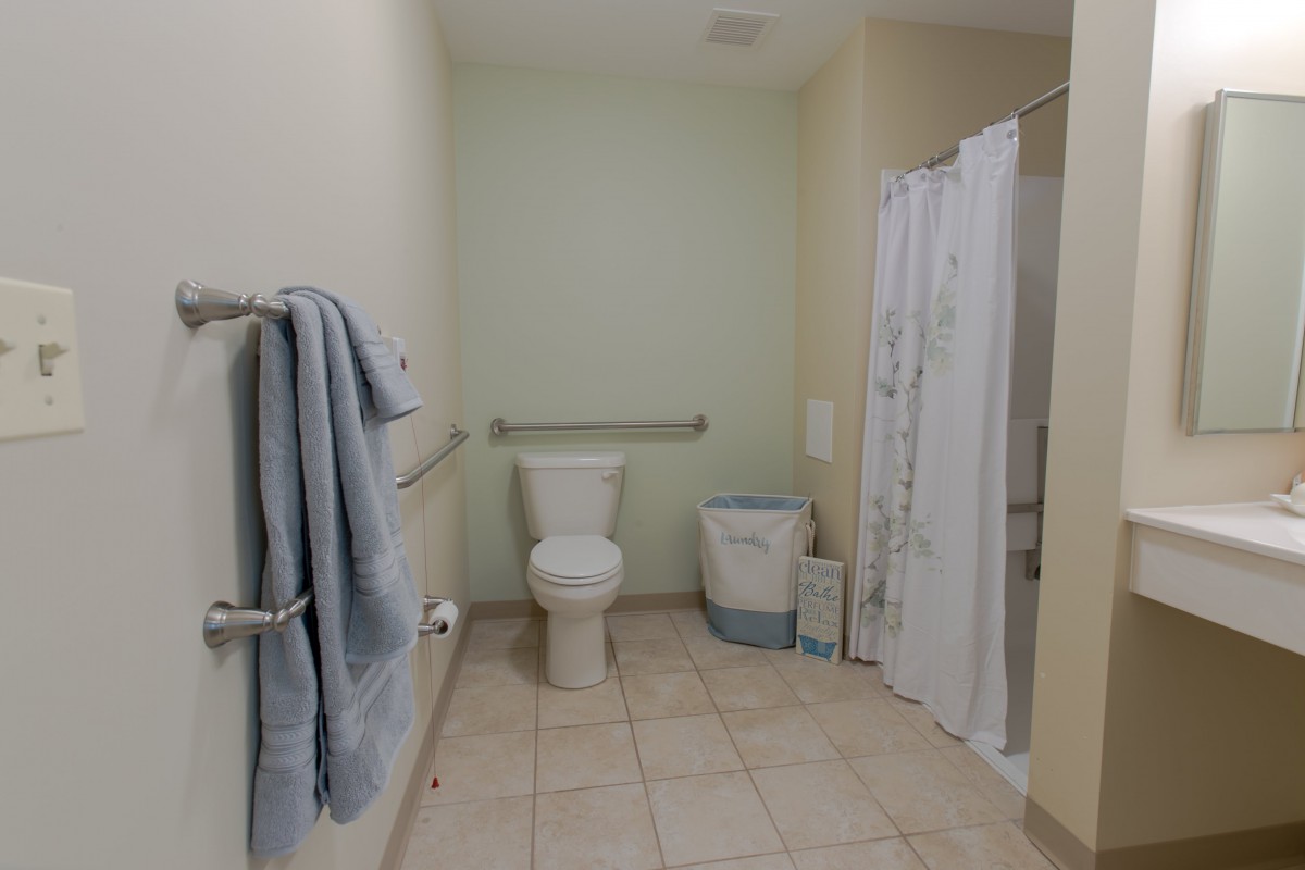 A clean and organized bathroom featuring a toilet, shower area, and neatly hung towels.