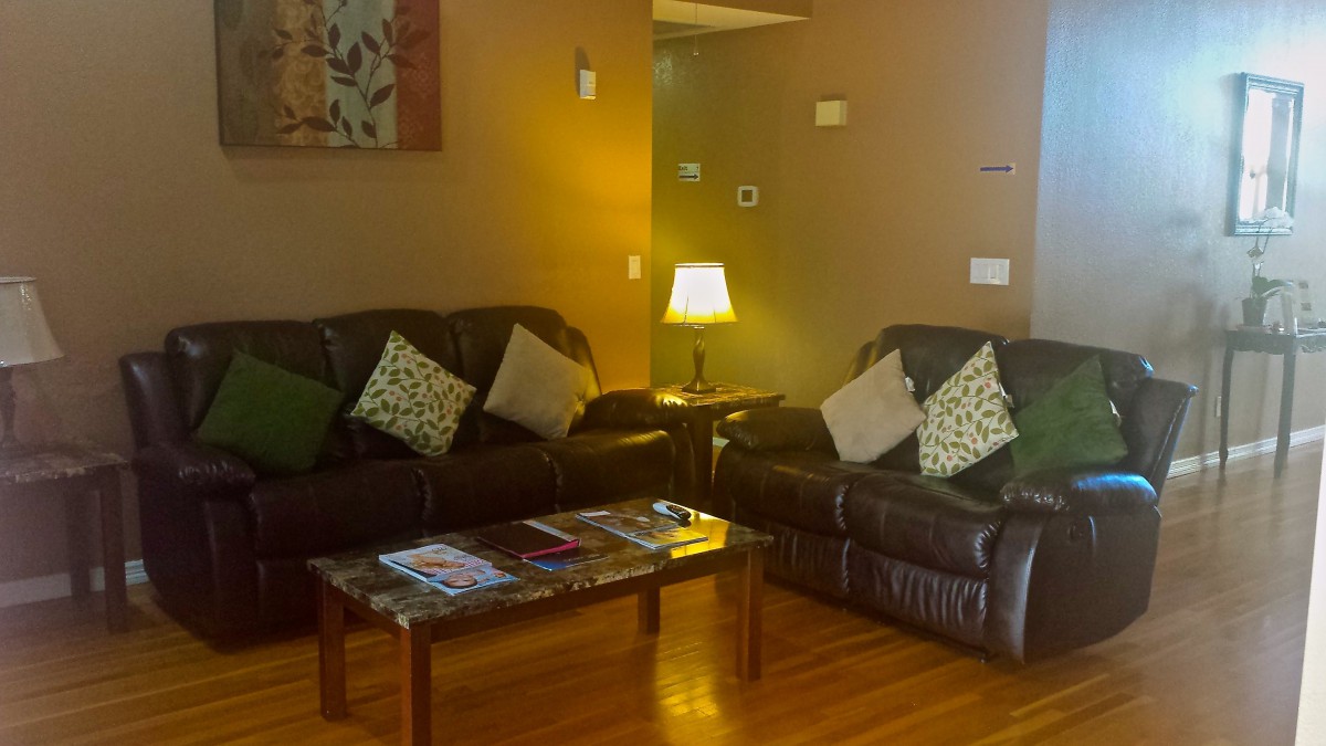 A cozy living room featuring two leather sofas, a coffee table with magazines, and a warm lamp.