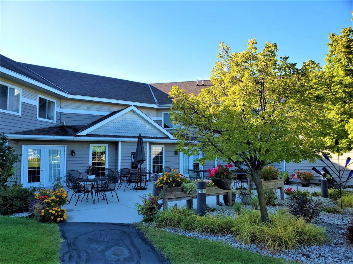 A beautiful house with a landscaped garden and patio area on a sunny day.