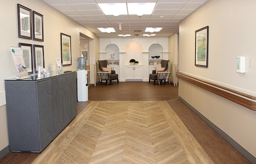A well-lit hallway featuring wooden flooring and artwork on the walls, leading to a cozy seating area.
