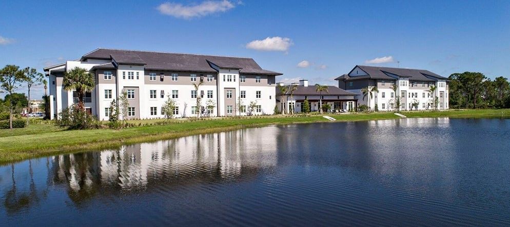 A beautiful building reflected in a serene lake under a clear blue sky.