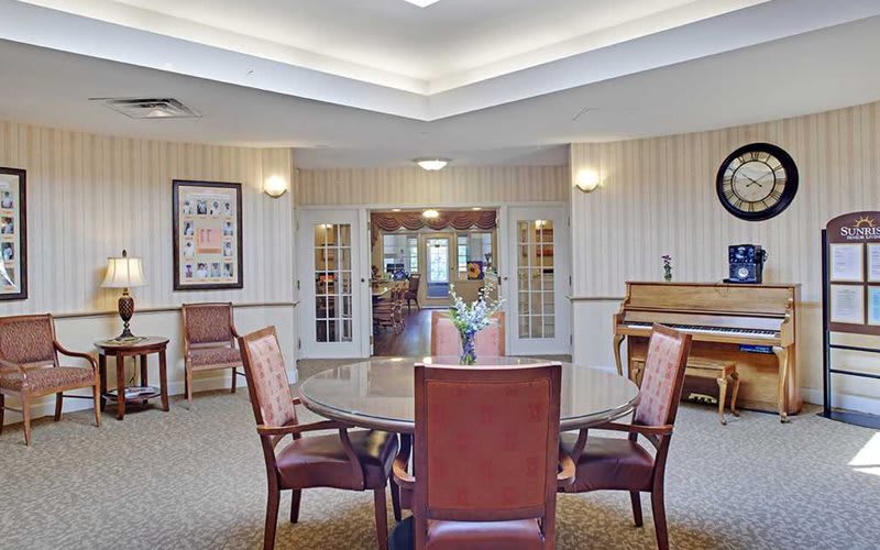 A cozy room with a table surrounded by chairs and a piano in the corner.