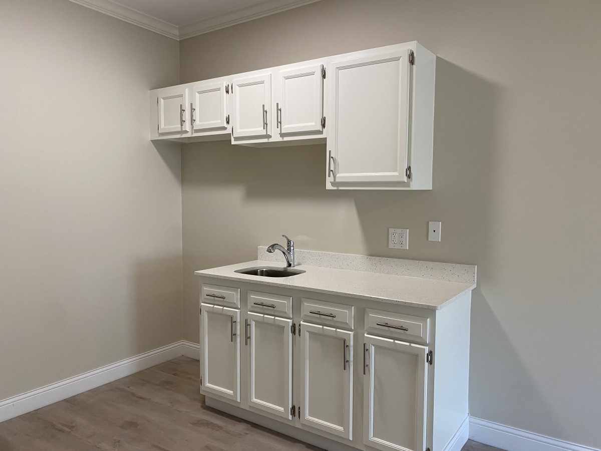 A minimalist kitchen with white cabinets and a small sink.