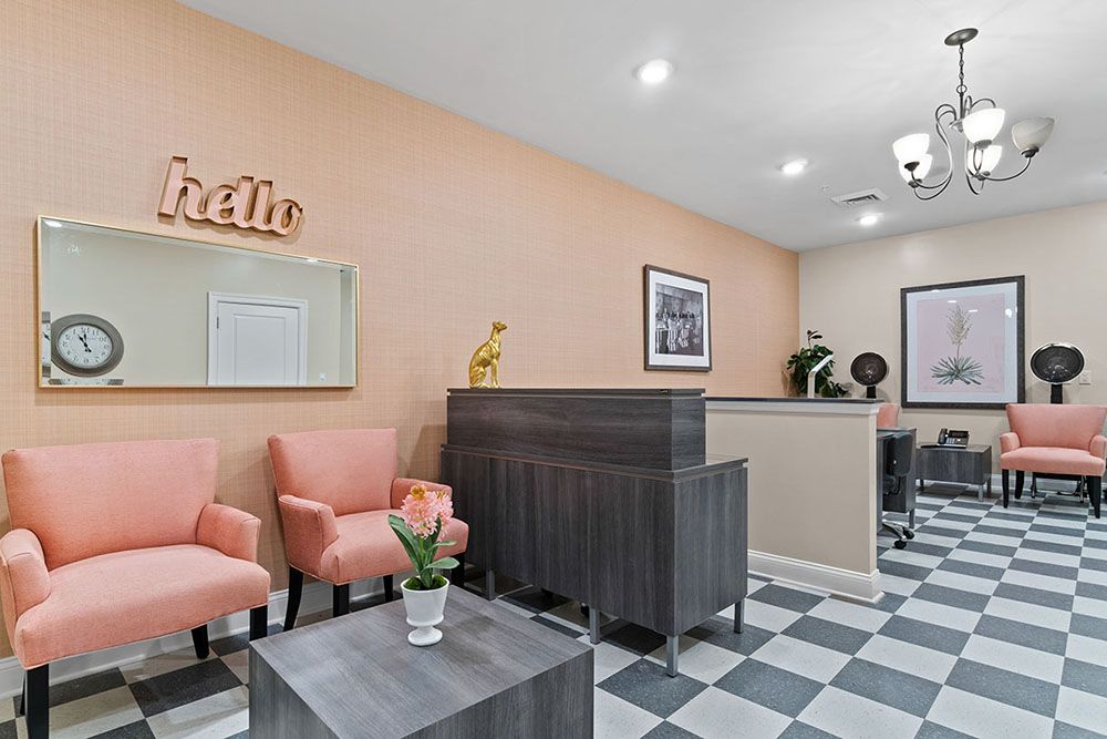 A modern office reception area with pink chairs and a checkered floor.