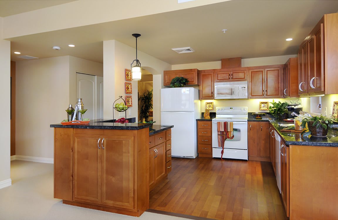 A modern kitchen featuring wooden cabinets, an island, and standard appliances.