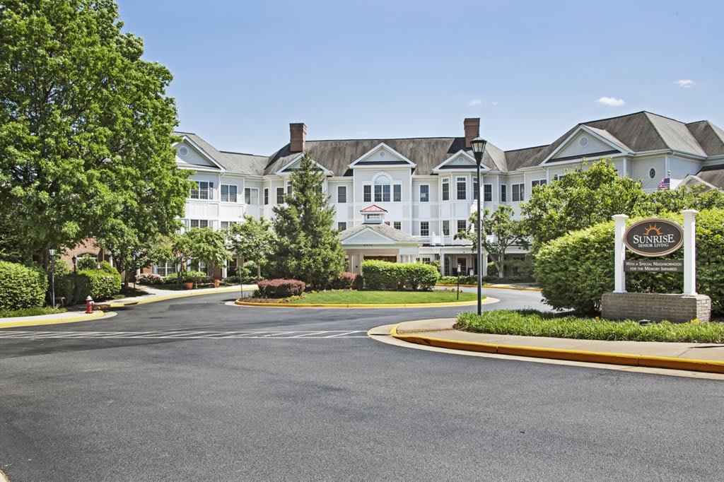 A residential-style building with a landscaped driveway and surrounding greenery.
