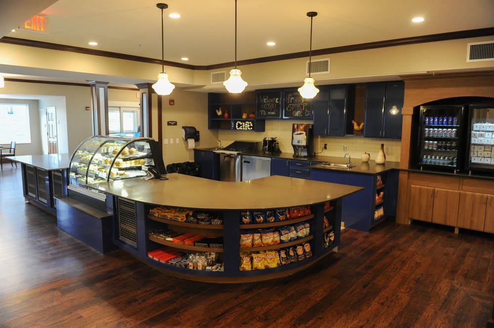 A modern cafe interior featuring a curved counter with a display case and snacks on wooden flooring.