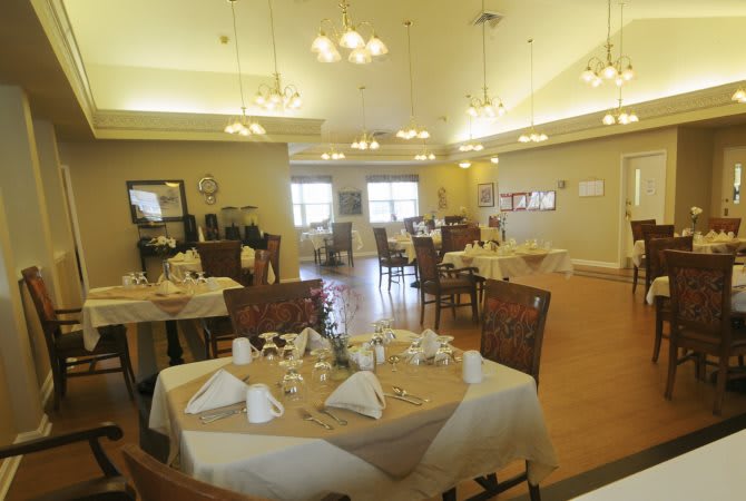 An elegantly set dining room with neatly arranged tables and chairs under warm lighting.