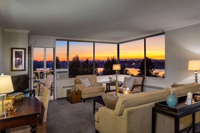 A cozy living room with modern furniture and large windows offering a breathtaking sunset view.